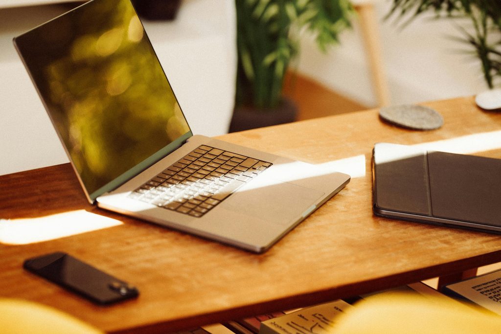 Ordenador portátil sobre una mesa, en ella también se pueden observar una tablet y un móvil